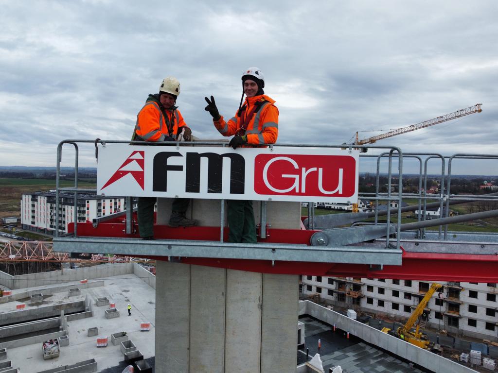 Dwaj technicy 7krane w odzieży ochronnej na platformie żurawia wieżowego FM Gru